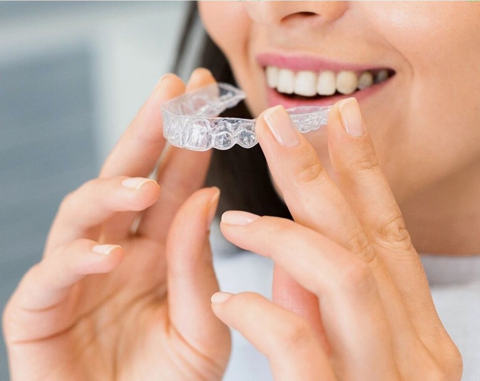 Patient with Clear Aligner — Custom Lab-Fabricated Transparent Orthodontic Appliance Patient holding a clear aligner tray — custom fabricated by dental lab from digital scan for orthodontic treatment