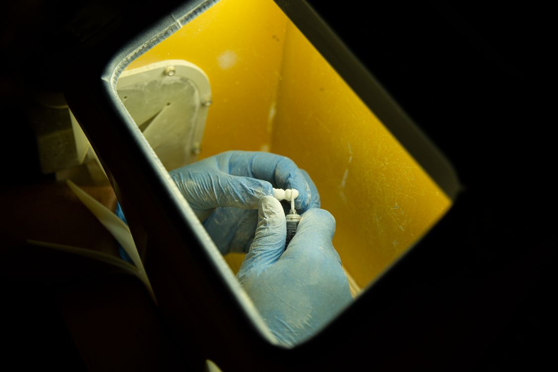 Dental technician hand-layering ceramic porcelain on a crown restoration — skilled craftsmanship in dental laboratory